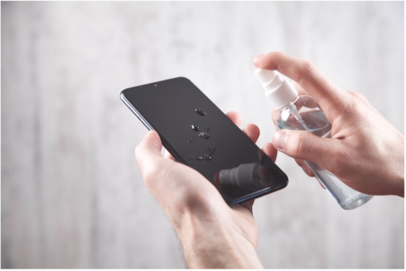 A person spraying a phone with a spray bottle