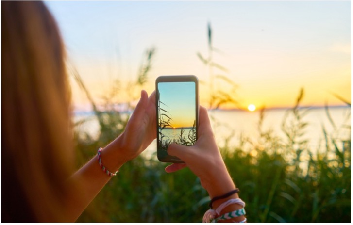 A person taking a picture of a sunset