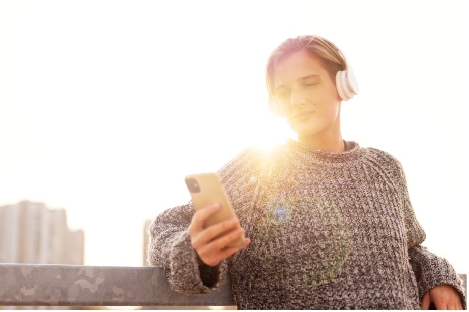 A person wearing headphones and holding a phone