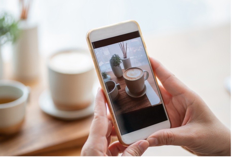 A person holding a phone with a picture of coffee cups